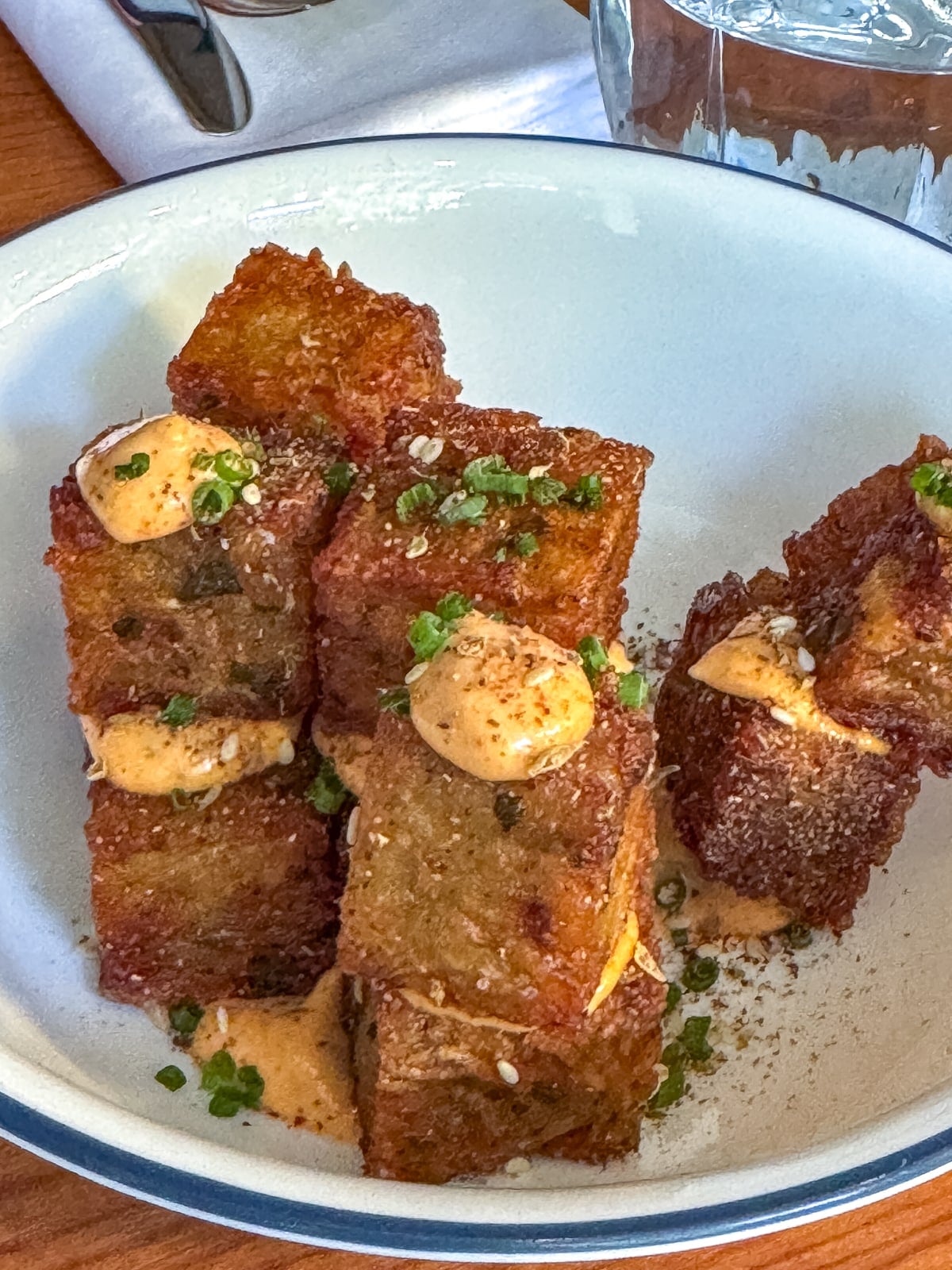 A plate of crispy fried potato cubes topped with dollops of creamy sauce and garnished with chopped chives&mdash;a must-try treat when exploring the top Things to Do in Roanoke VA.