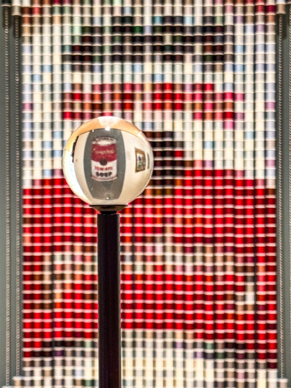 A glass sphere on a stand reflects a wall display of colorful spools of thread arranged in a pattern&mdash;an inspiring scene for creative souls seeking unique things to do in Roanoke VA.