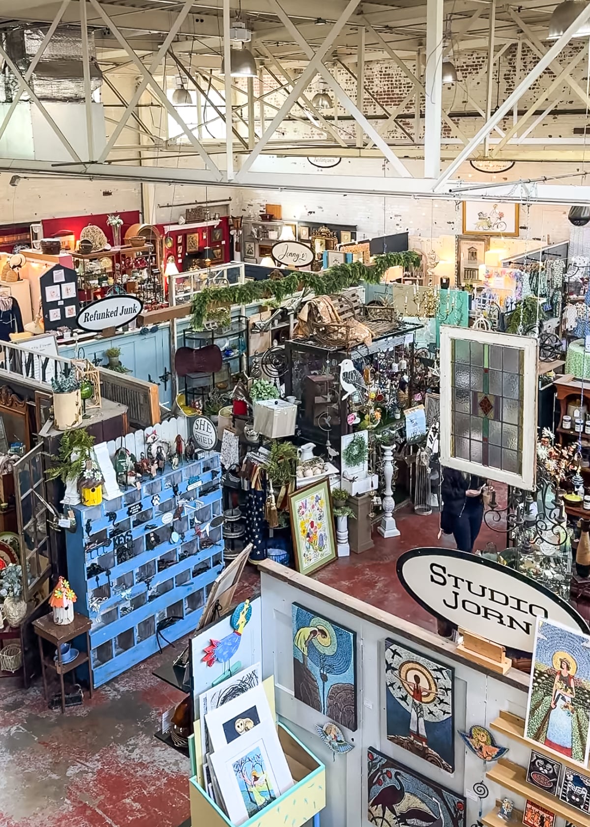 Discover one of the top Things to Do in Roanoke VA at Black Dog Savage, featuring vintage furniture, artwork, decorative items, houseplants, and vendor signs beneath a soaring industrial ceiling.