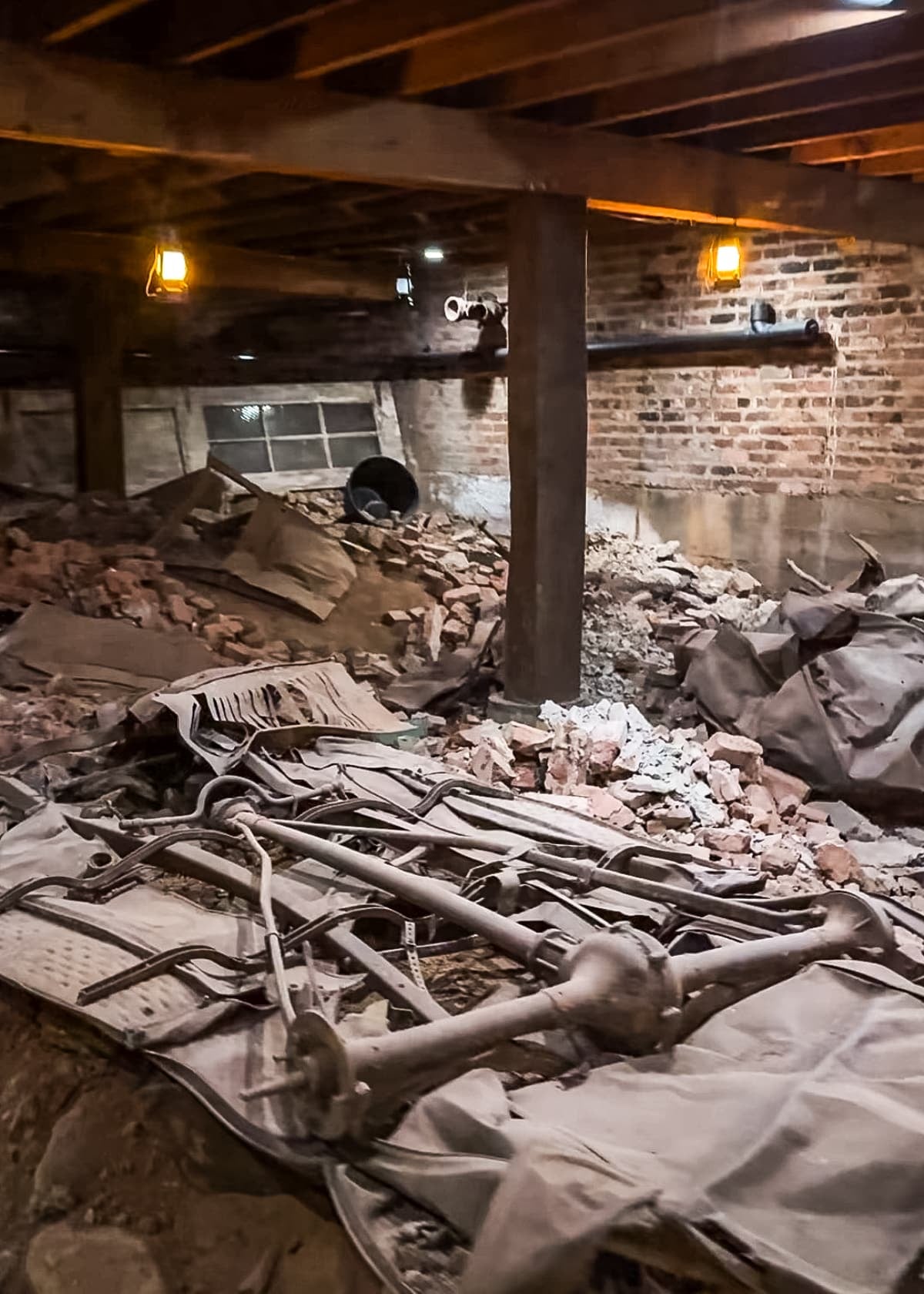 A dimly lit basement with exposed beams, brick walls, debris, and scattered metal parts on the ground feels worlds away from the lively attractions and things to do in Roanoke VA.