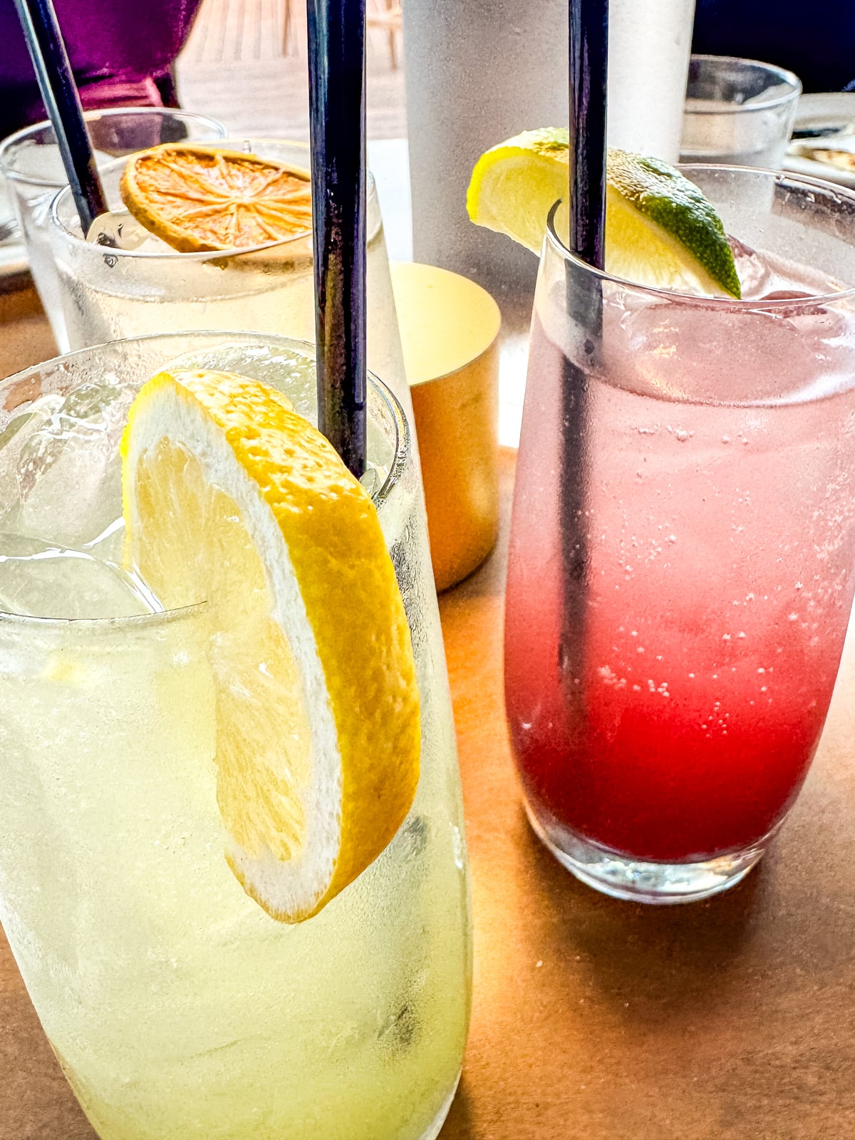 Two glasses of iced drinks, one yellow with a lemon slice and one pink with a lime wedge, sit on a table&mdash;refreshing treats to enjoy while exploring Things to Do in Roanoke VA.